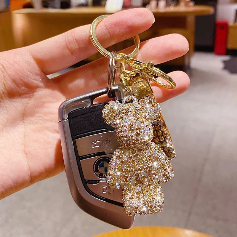 Hand holding car keys with a sparkling rhinestone bear keychain attached to the keyring