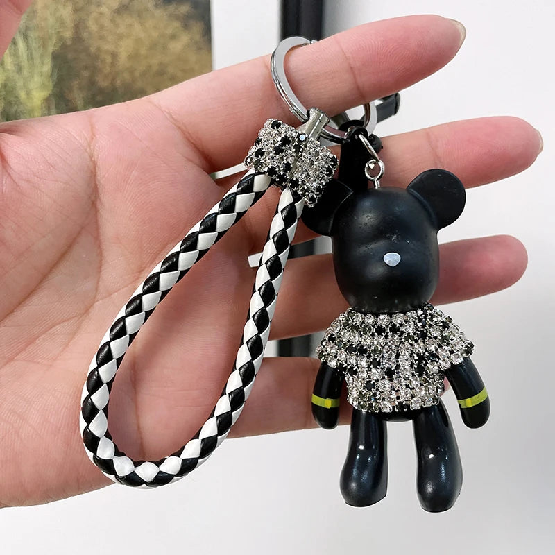 Cute rhinestone bear keychain with black body and sparkling rhinestone outfit held in hand