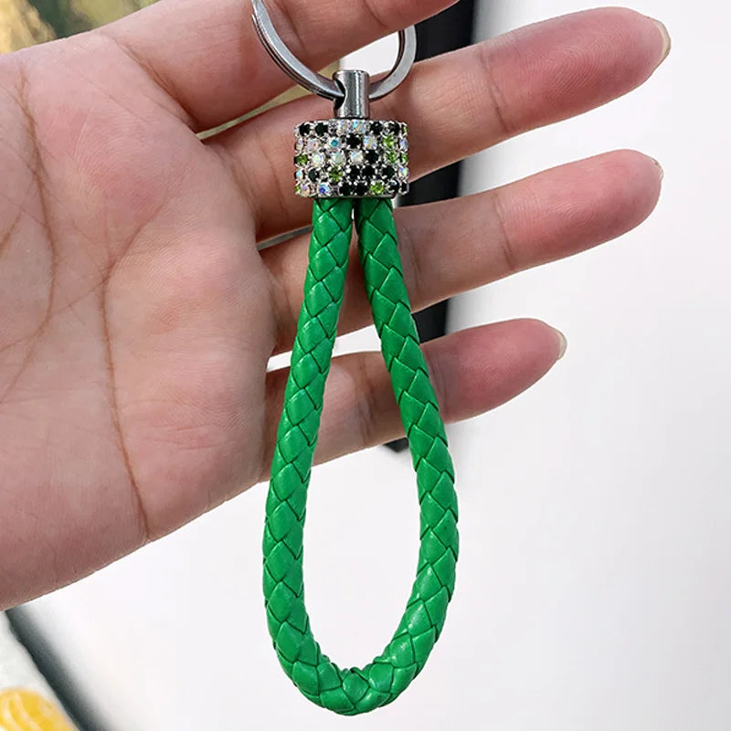 Cute rhinestone bear keychain with green braided leather loop and silver ring held in hand