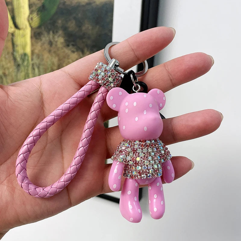 Cute rhinestone bear keychain in pink with polka dots and braided strap held in hand