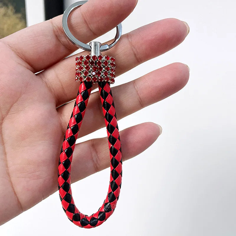 Hand holding a cute rhinestone bear keychain with red and black braided loop and sparkling rhinestone detail