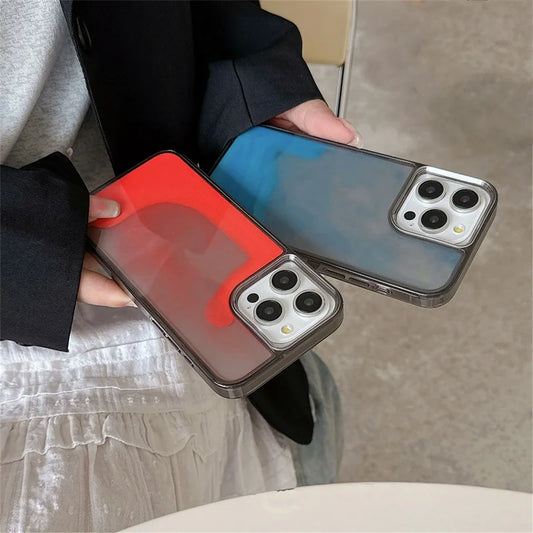 Two luminous sand iPhone cases in red and blue colors held by a person wearing a black jacket