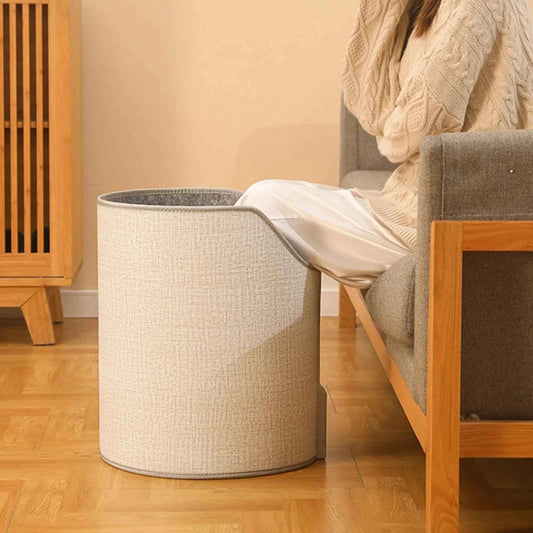 Portable heated foot warmer for home in beige with textured fabric used by person sitting on couch