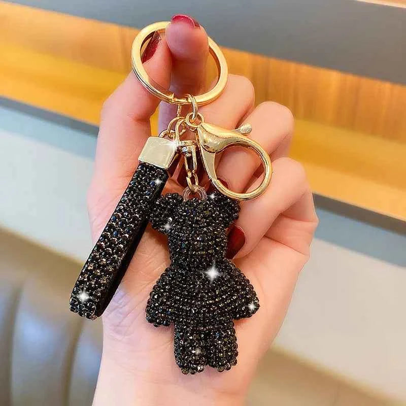 Black rhinestone bear keychain with gold clasp and matching black rhinestone strap held in hand