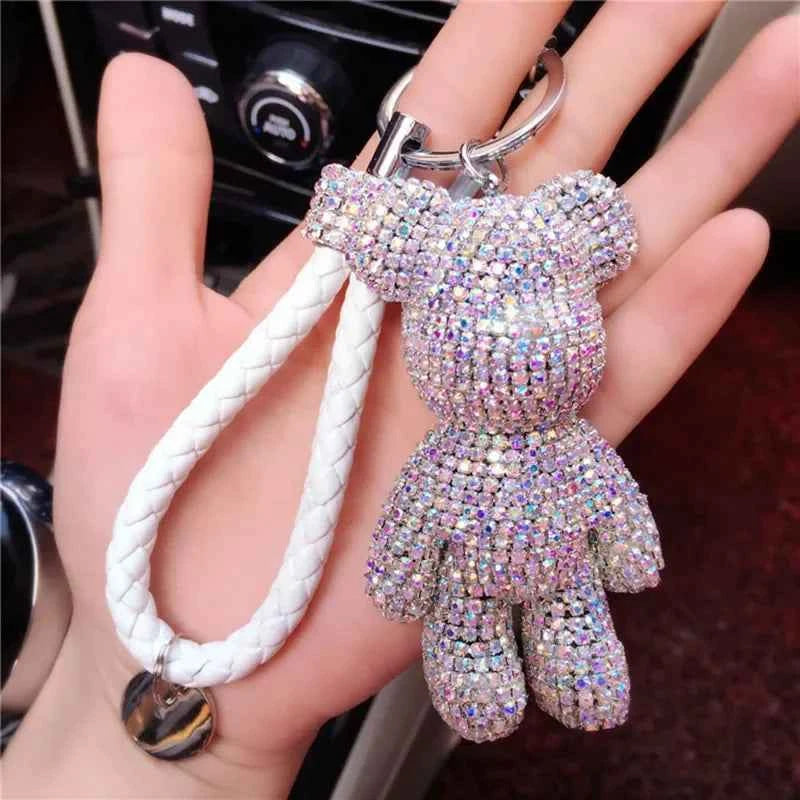 Sparkling rhinestone bear keychain with white braided strap held in hand