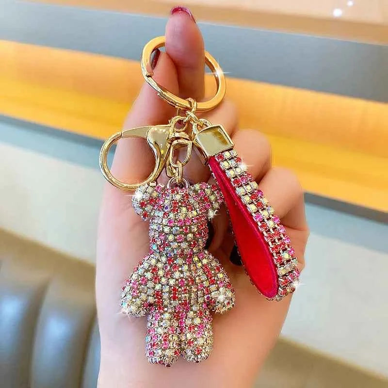 Hand holding a rhinestone bear keychain with pink and clear crystals and a matching rhinestone strap
