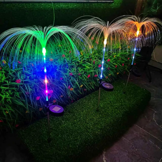 DFShop colorful solar jellyfish garden lights glowing in green, blue, and orange on a garden bed at night