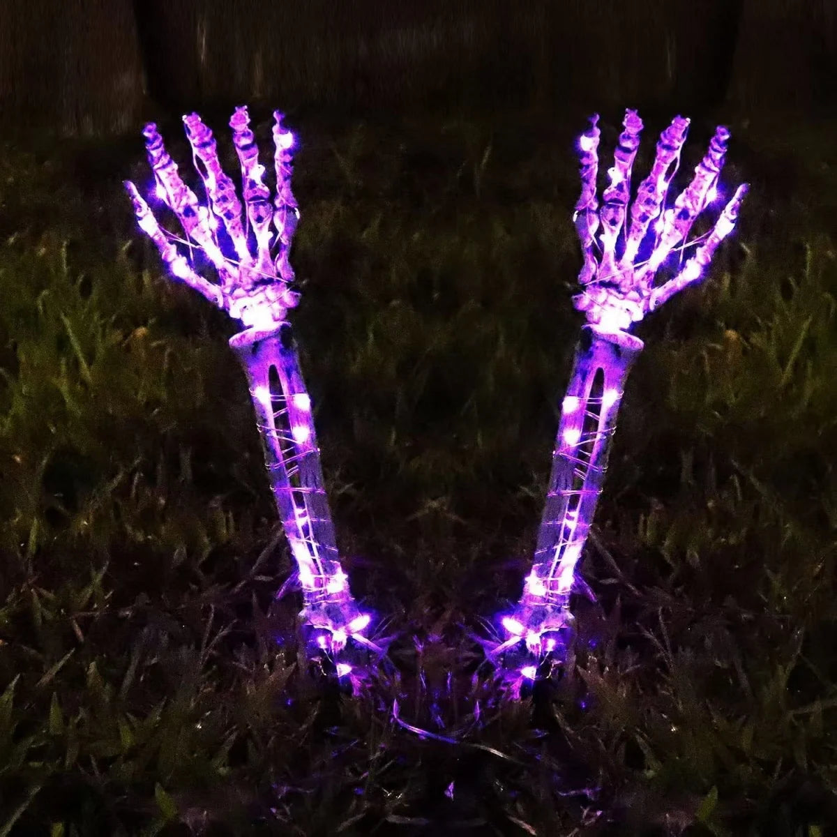 Halloween ghost hand lights glowing purple skeleton hands decoration on grass for spooky Halloween ambiance
