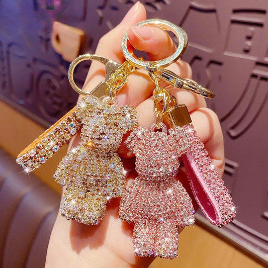 Two rhinestone bear keychain charms in gold and pink held in hand with matching rhinestone straps