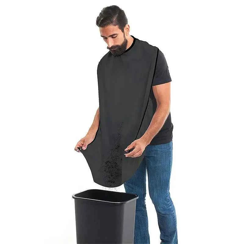 Man using black beard trimming bib for men to catch hair clippings while grooming over trash bin