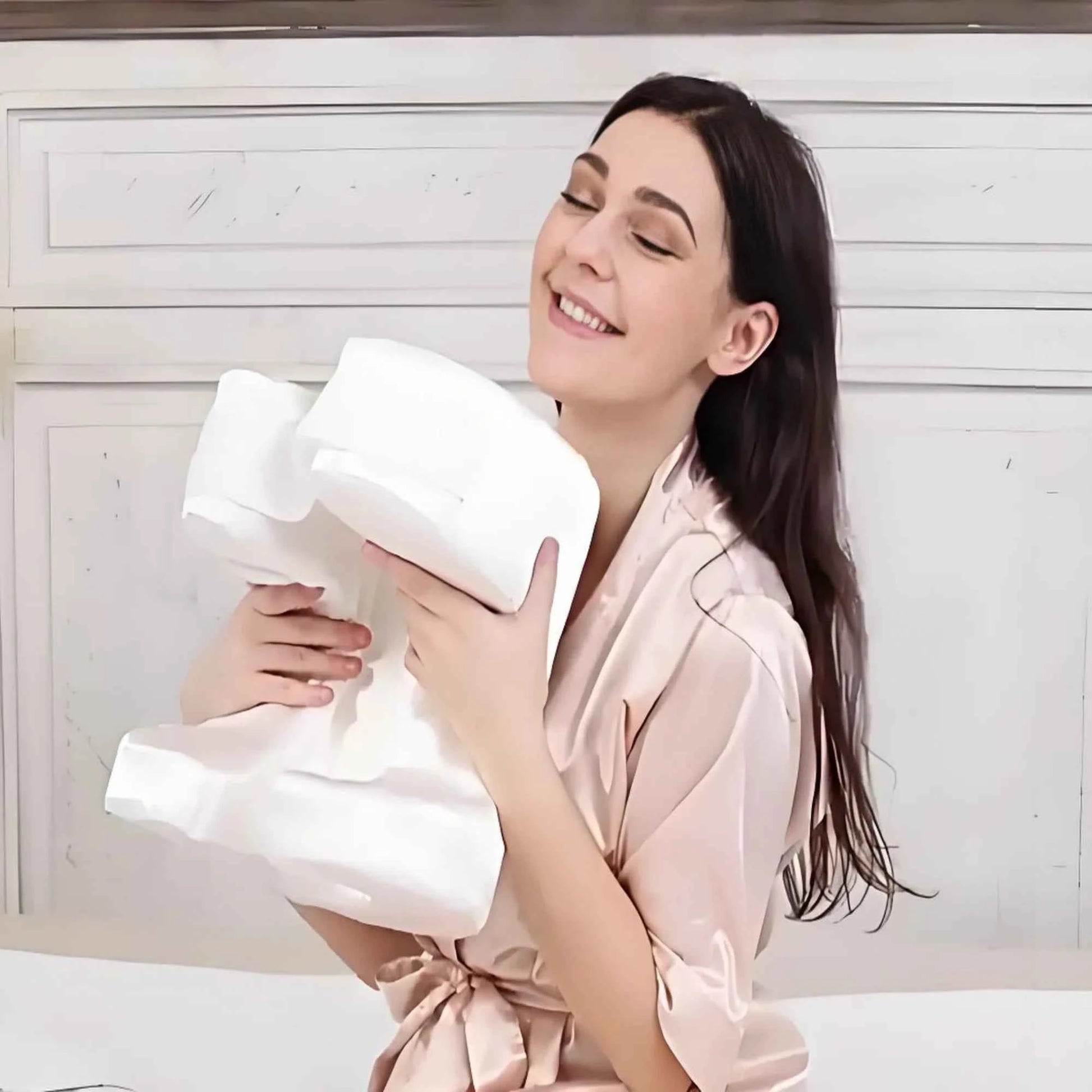 Woman in satin robe holding a white anti wrinkle sleep pillow designed for comfortable facial support