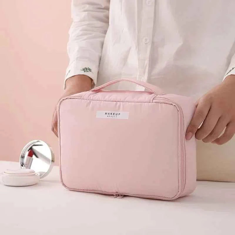 Pink portable cosmetic organizer with handle held by person wearing white shirt on table