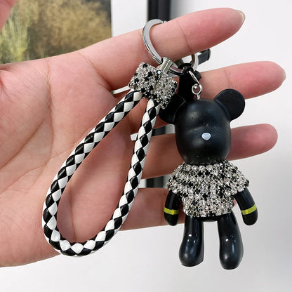 Cute rhinestone bear keychain with black body and sparkling rhinestone outfit held in hand
