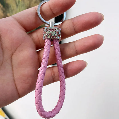 Hand holding cute rhinestone bear keychain with pink braided loop and sparkly charm