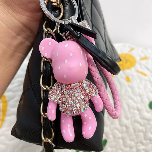 Cute rhinestone bear keychain in pink with white polka dots attached to a black handbag