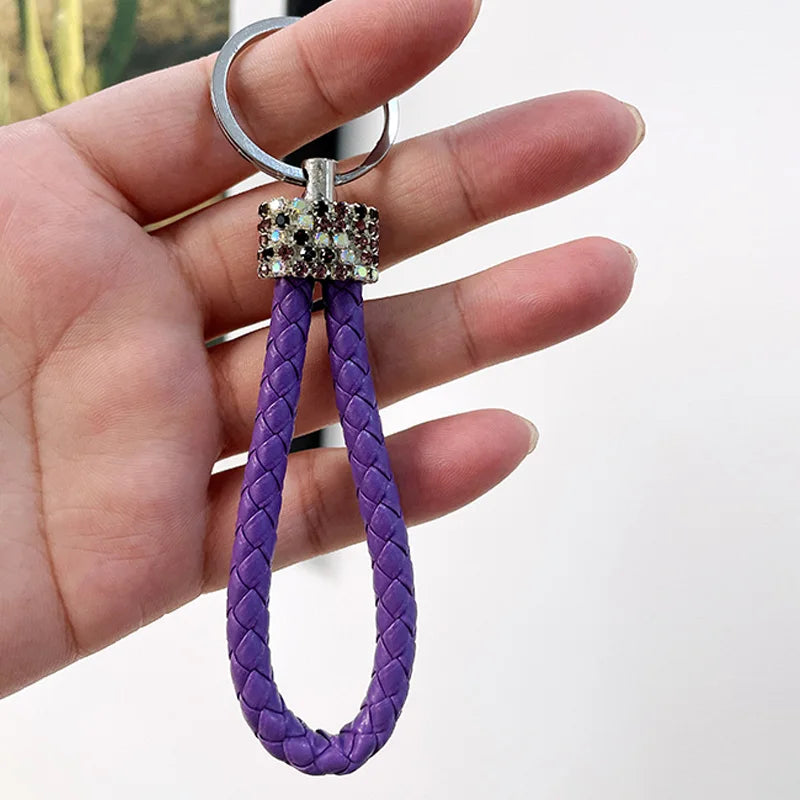 Hand holding a cute rhinestone bear keychain with purple braided loop and rhinestone bear charm