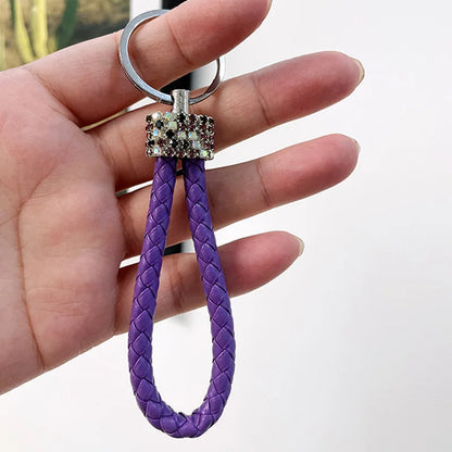 Hand holding a cute rhinestone bear keychain with purple braided loop and rhinestone bear charm