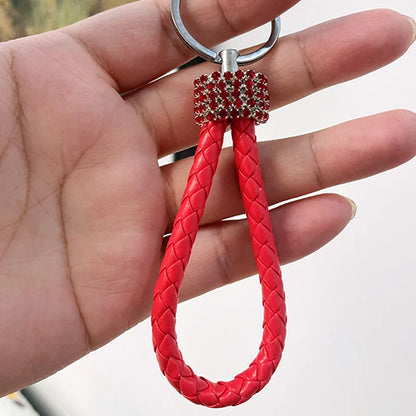 Hand holding cute rhinestone bear keychain with red braided loop and silver ring