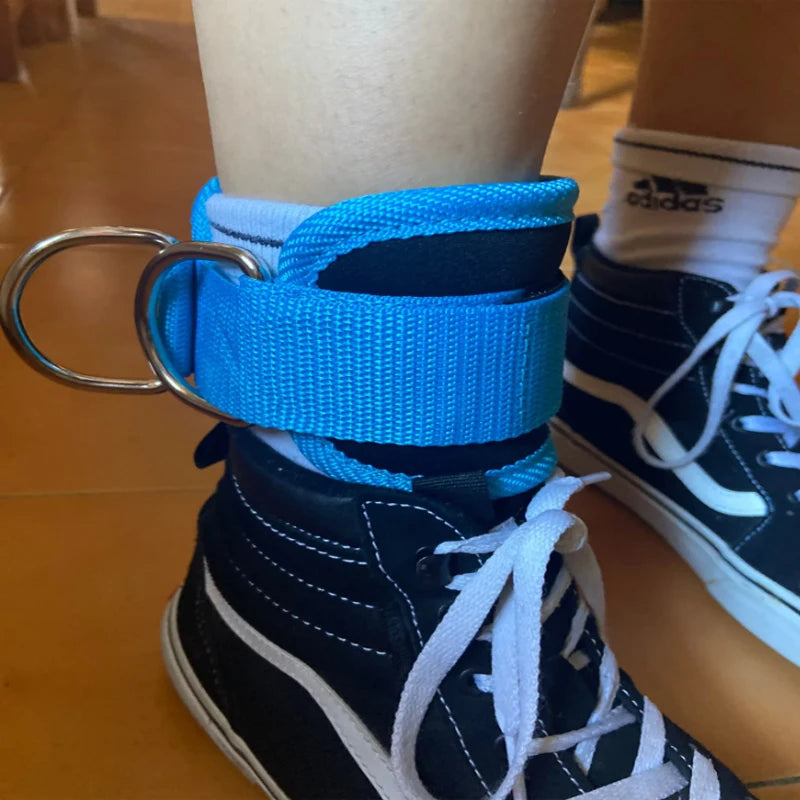 Blue double d-ring ankle straps for gym wrapped around black high-top sneakers with white laces
