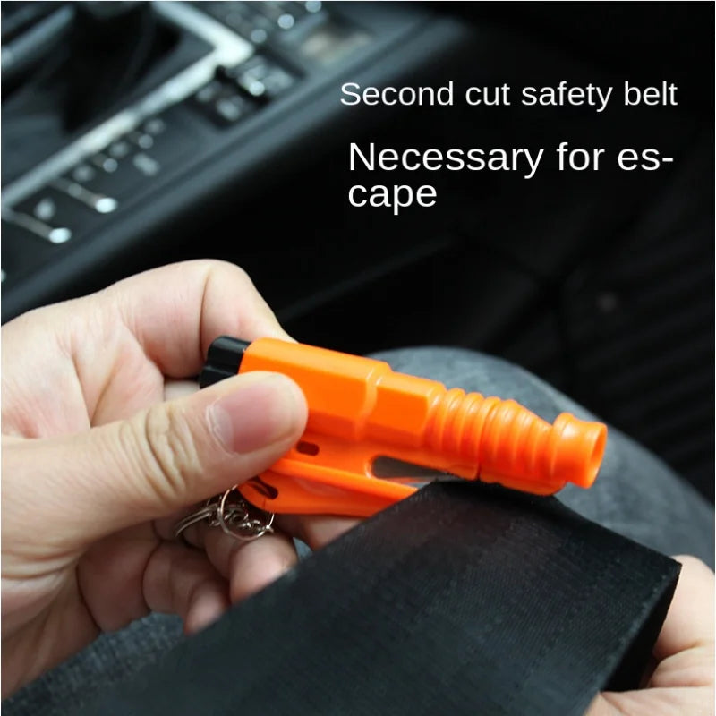 Hand using orange keychain safety hammer to cut black car seatbelt for emergency escape