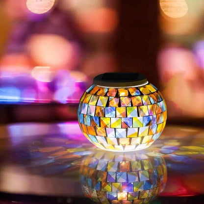 Colorful solar mosaic garden lights glowing with warm orange and blue tones on reflective surface