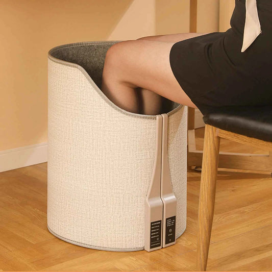 Portable heated foot warmer for home in beige fabric with a person using it while sitting on a chair
