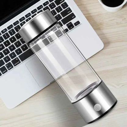 Sleek portable hydrogen water generator with silver base and clear bottle placed on laptop keyboard