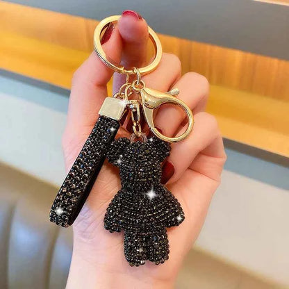 Black rhinestone bear keychain with gold clasp and matching black rhinestone strap held in hand