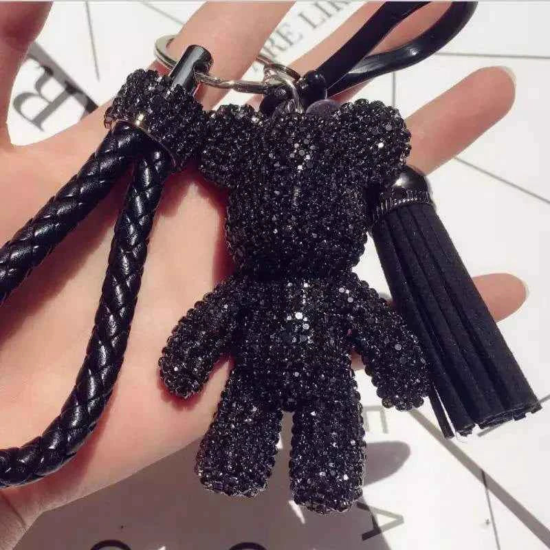 Black rhinestone bear keychain with braided strap and tassel held in hand