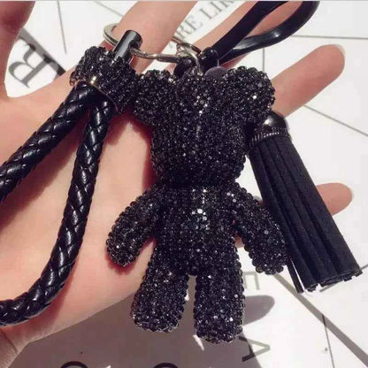 Black rhinestone bear keychain with braided strap and tassel held in hand