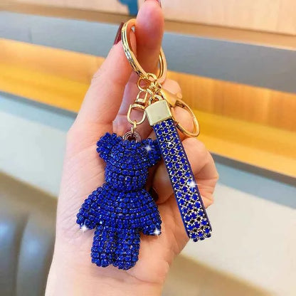 Hand holding a blue rhinestone bear keychain with a matching rhinestone strap and gold keyring