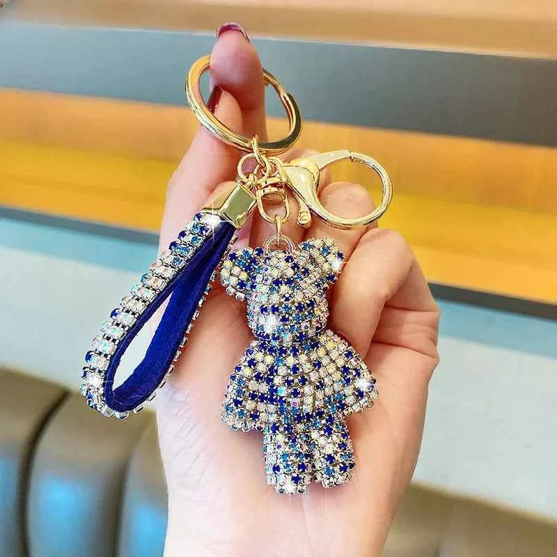 Rhinestone bear keychain with blue and clear crystals and matching strap held in hand
