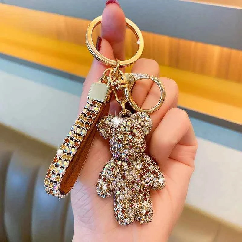 Hand holding a sparkling rhinestone bear keychain with a matching rhinestone strap attached to gold key rings
