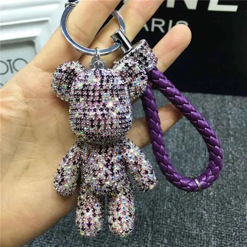 Sparkling rhinestone bear keychain with purple braided strap held in hand