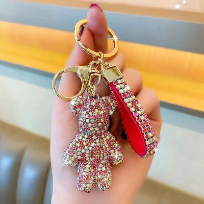 Hand holding a rhinestone bear keychain with pink and clear crystals and a matching rhinestone strap