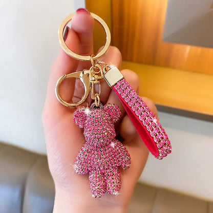 Pink rhinestone bear keychain with matching strap and gold keyring held in hand