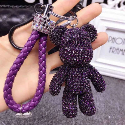 Purple rhinestone bear keychain with braided strap and sparkling stones held in hand