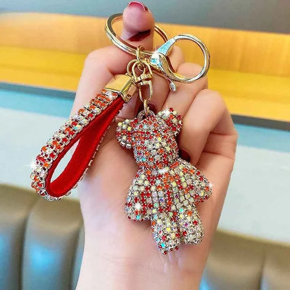 Hand holding a rhinestone bear keychain with sparkling crystal teddy bear and red rhinestone strap