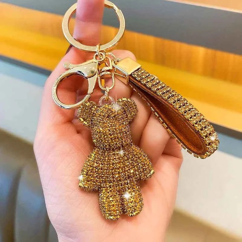 Gold rhinestone bear keychain with matching wrist strap and metal ring held in hand