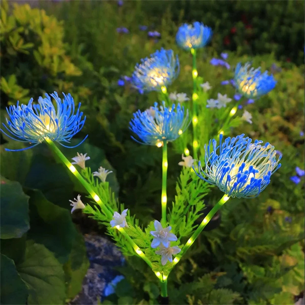 Blue solar flower garden lights glowing warmly with green stems in a lush outdoor garden setting