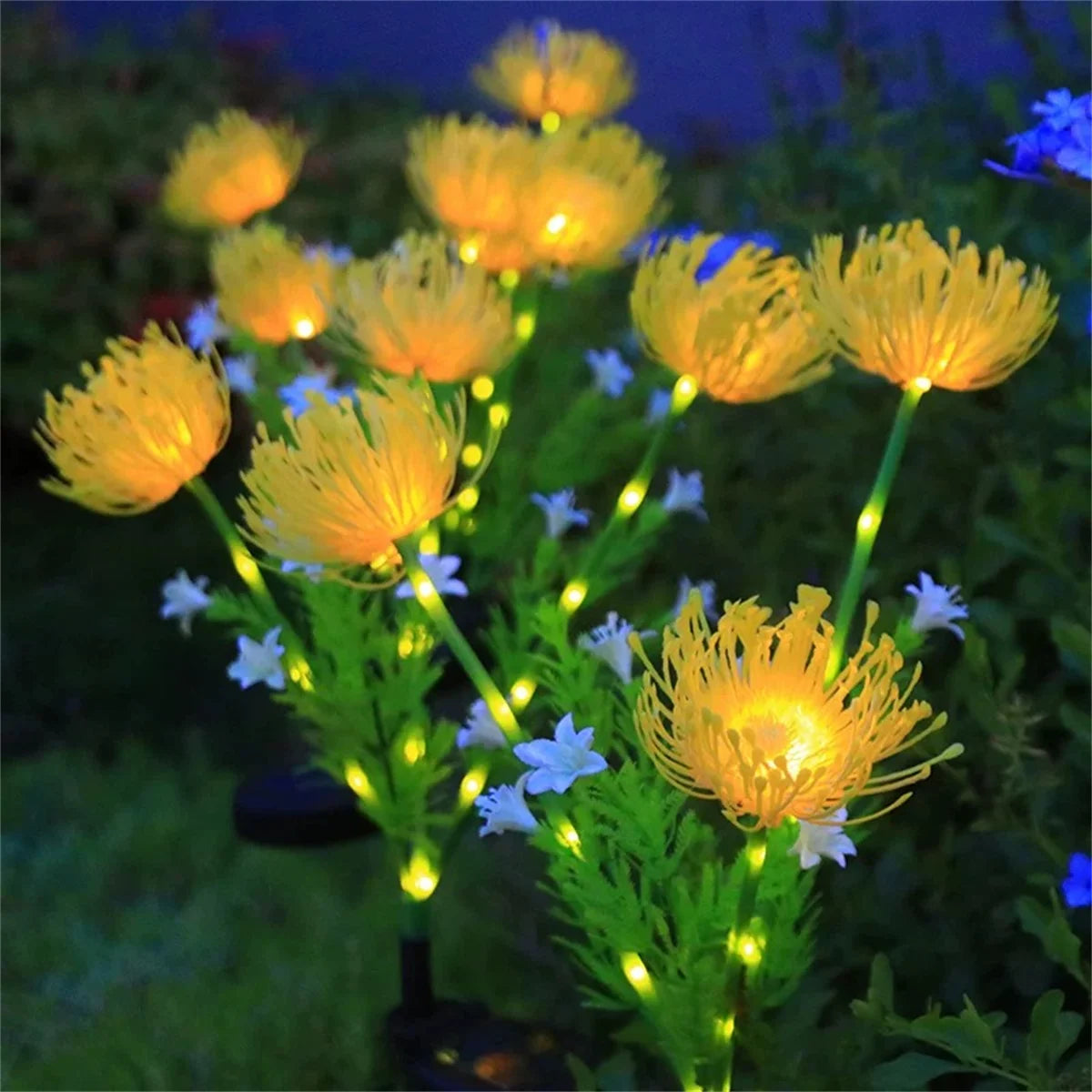 Yellow solar flower garden lights glowing in the dark amidst green plants and small white flowers