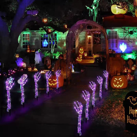 Halloween ghost hand lights glowing purple lining a spooky front yard pathway with Halloween decorations