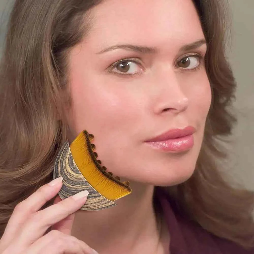 Woman using a deep cleansing facial brush with yellow bristles and wood-patterned handle on her cheek