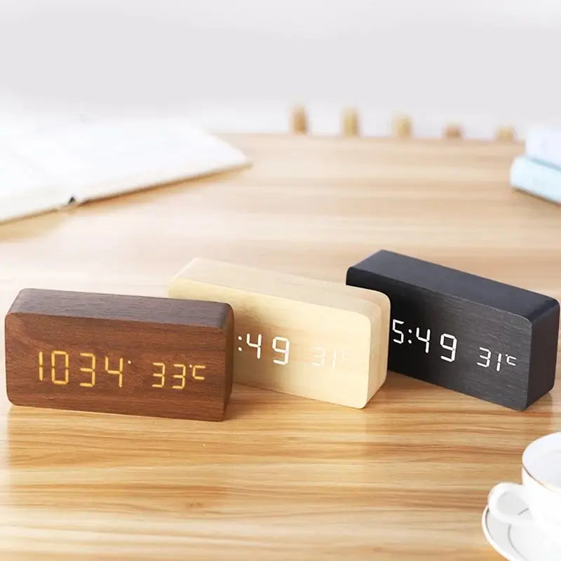 Set of three wooden digital alarm clocks in dark brown, light beige, and black on a wooden table